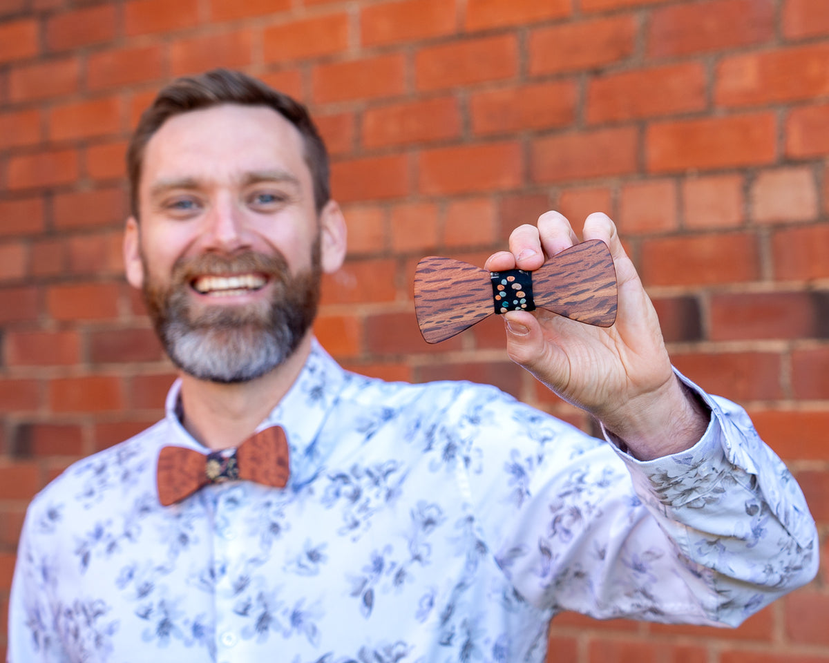 Close-up of a handmade Australian hardwood bowtie held in front of the maker